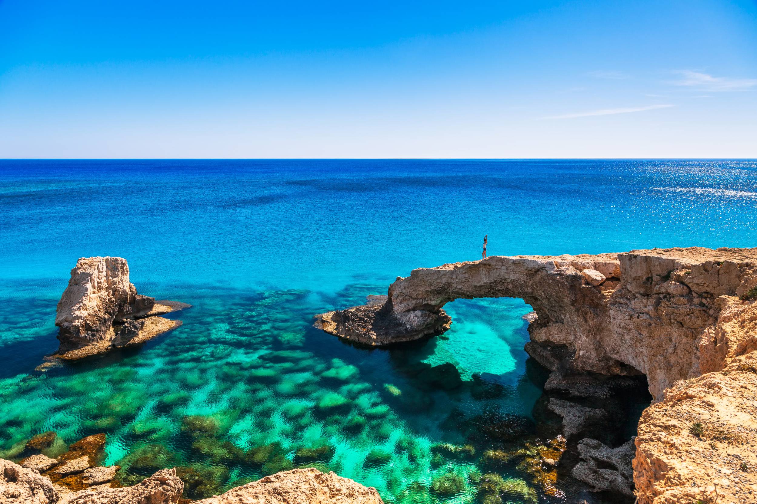 Γυναίκα στην όμορφη φυσική αψίδα βράχου κοντά στην Αγία Νάπα, το Κάβο Γκρέκο και τον Πρωταρά στο νησί της Κύπρου, στη Μεσόγειο Θάλασσα. Θρυλικοί λάτρεις της γέφυρας. Καταπληκτική γαλαζοπράσινη θάλασσα και ηλιόλουστη μέρα.