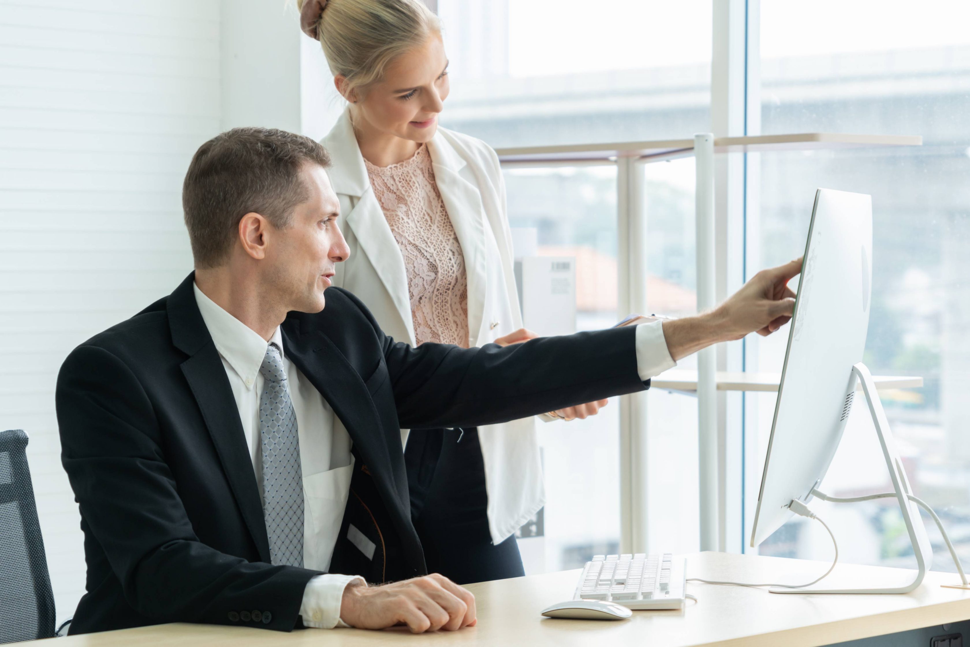 Two business people talk project strategy at office meeting room. Businessman discuss project planning with colleague at modern workplace while having conversation and advice on financial data report.