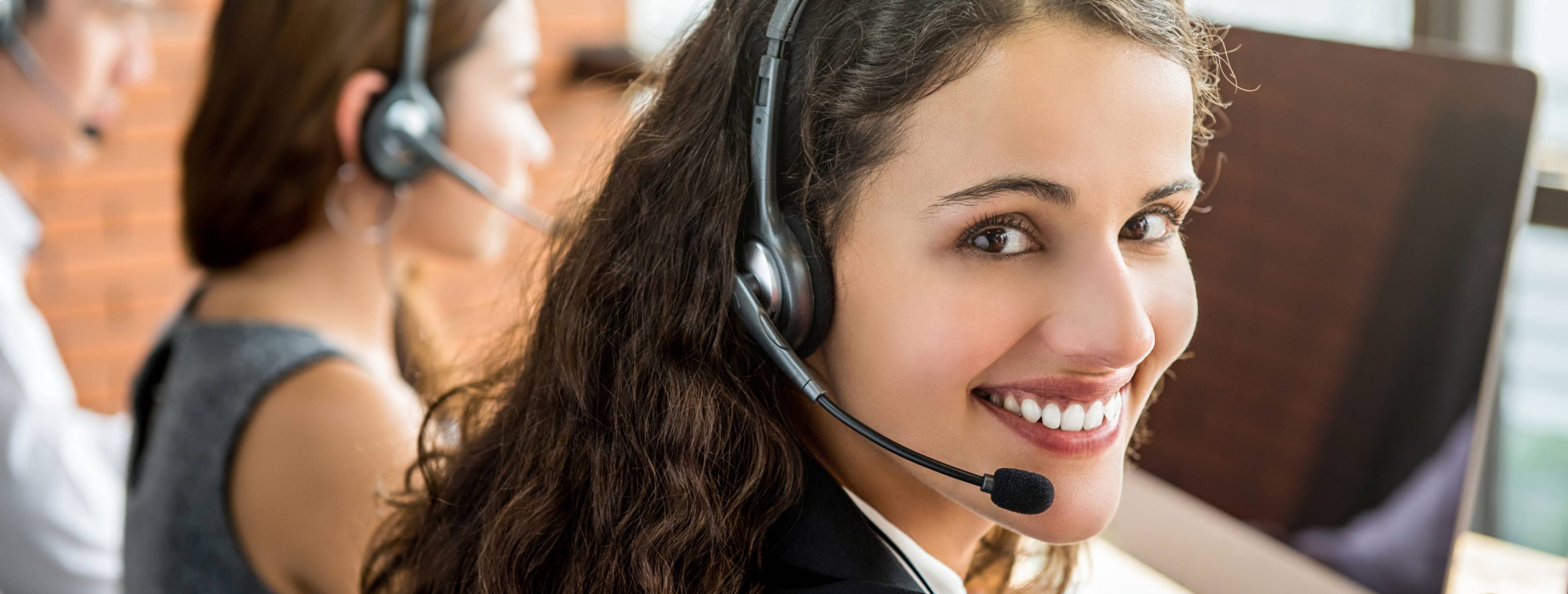 Smiling female telemarketing customer service agent working in call center.