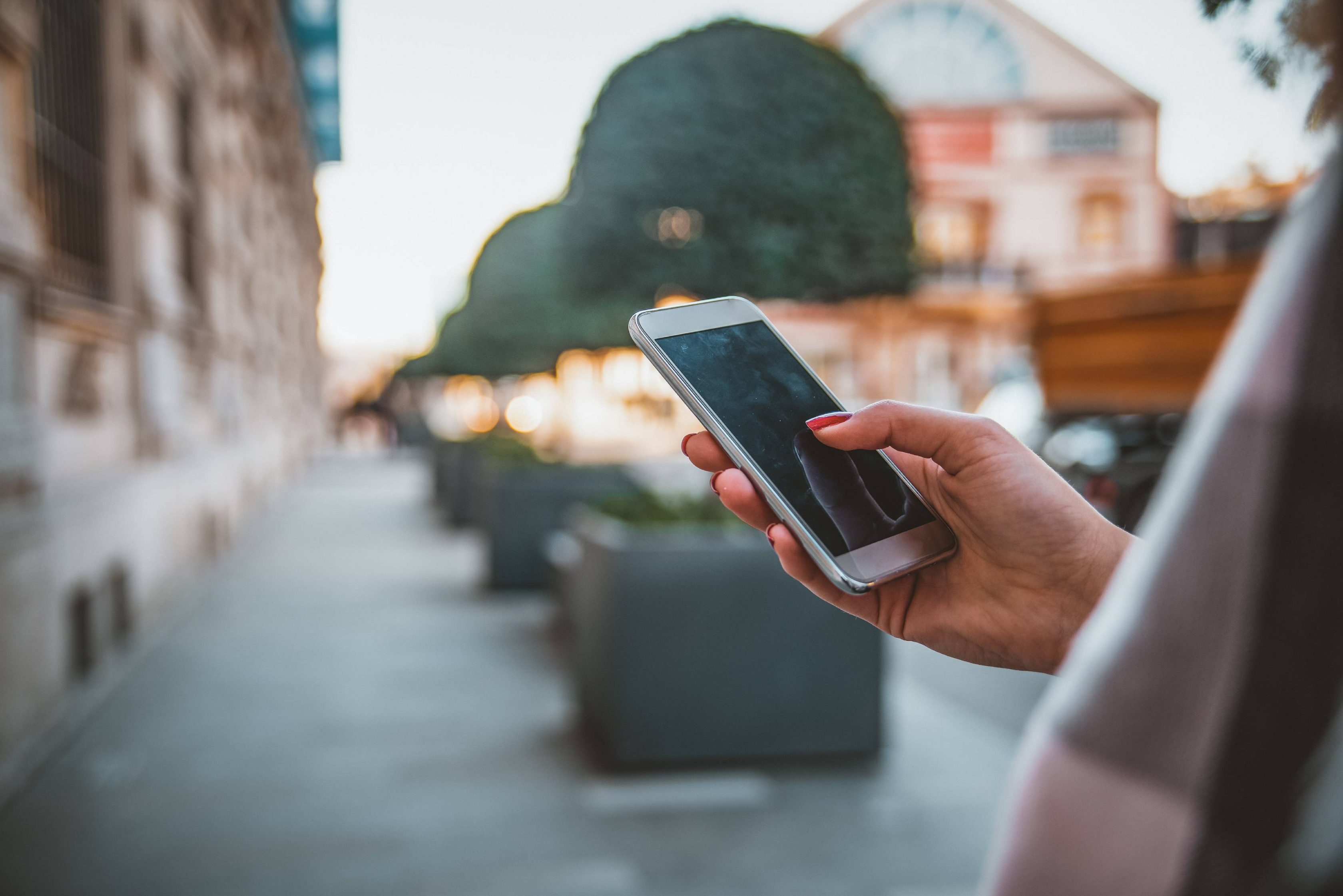 Woman typing text message on smart phone outdoors.